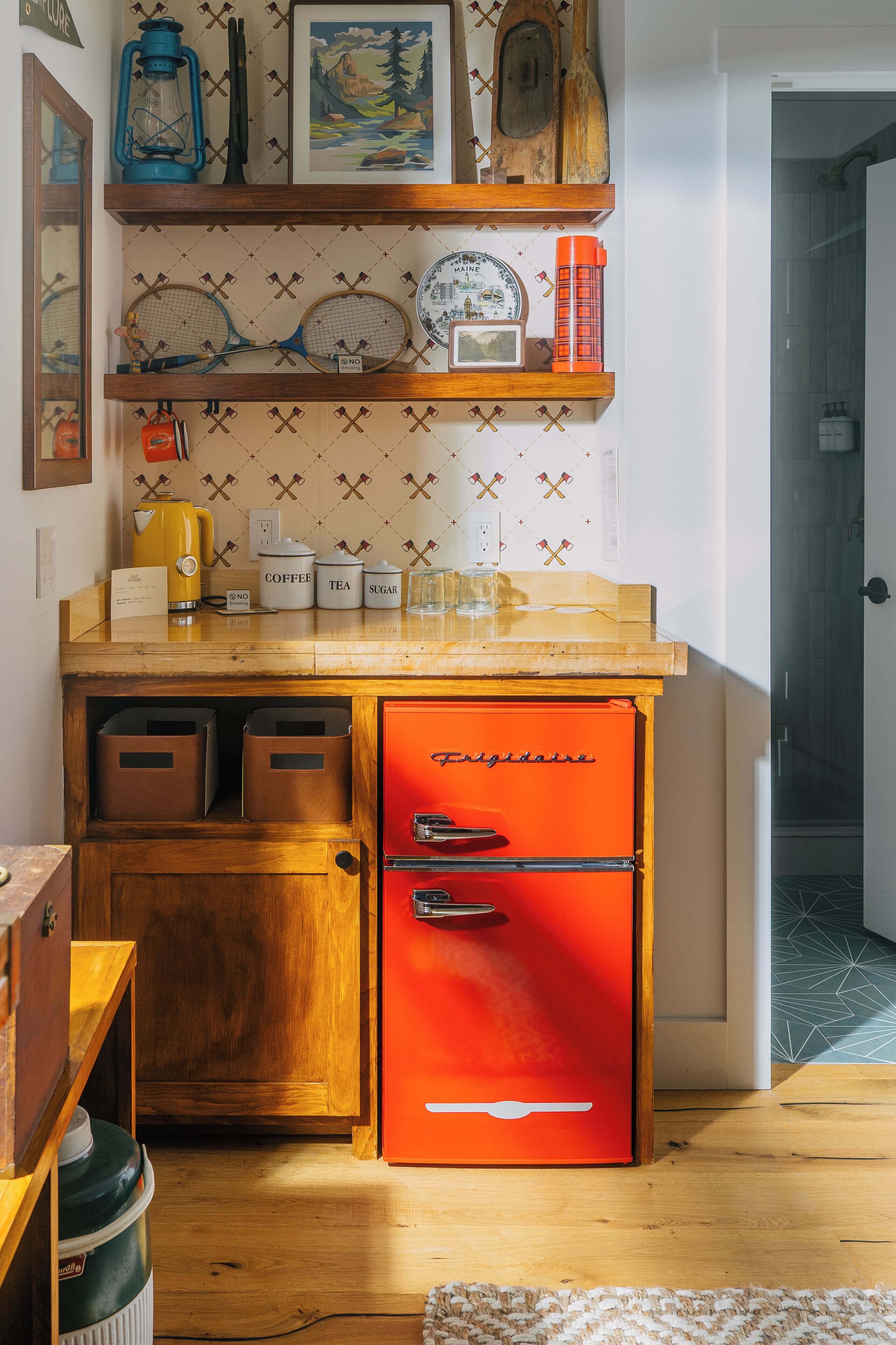 Une cuisine compacte avec un réfrigérateur rouge, des placards en bois et un plan de travail sur lequel sont disposés des ustensiles de cuisine.