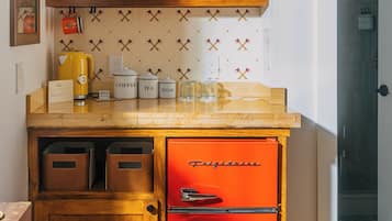 Une cuisine compacte avec un réfrigérateur rouge, des placards en bois et un plan de travail sur lequel sont disposés des ustensiles de cuisine.