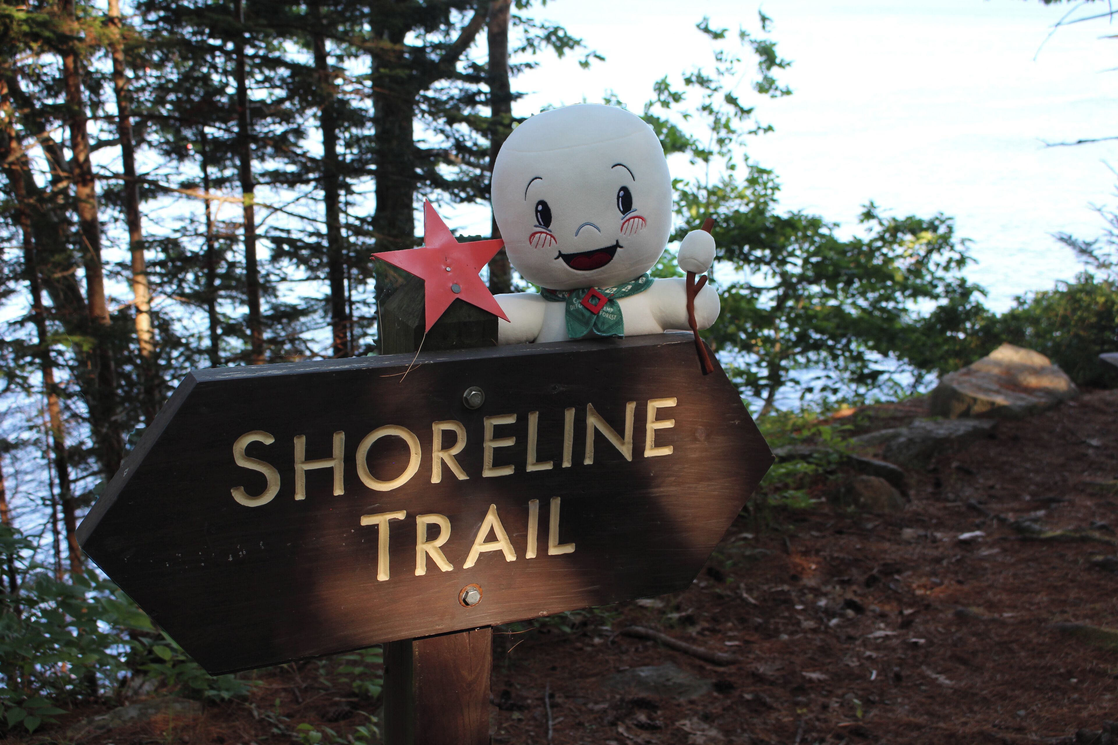 Ein hölzernes Schild mit dem Schriftzug „SHORELINE TRAIL“ und eine Stofftierfigur mit einem Stern obenauf.