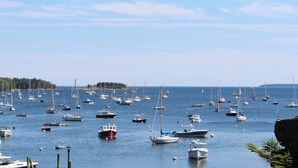A marina with numerous boats docked, surrounded by calm water and a clear sky. - Camp DeForest (Lincolnville)