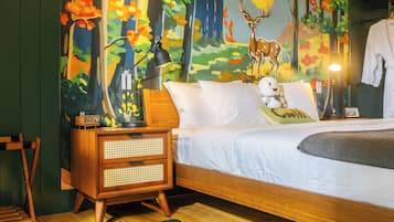 A bedroom with a bed, nightstand, lamp, and a wall mural.