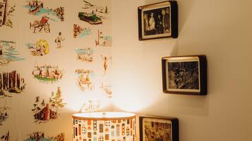 A room with a wall decorated with various illustrations, a lamp, framed pictures, and a 'MAINE' pennant.