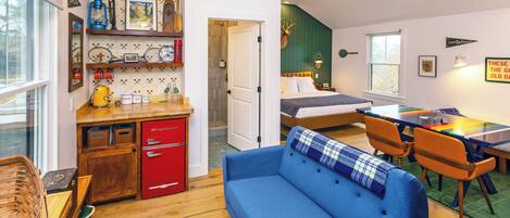 A cozy room with a blue sofa, a wooden dining table, and a bed with a green headboard.