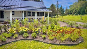 A house with a solar panel roof, surrounded by a well-maintained garden with various plants and flowers. - Camp DeForest (Lincolnville)