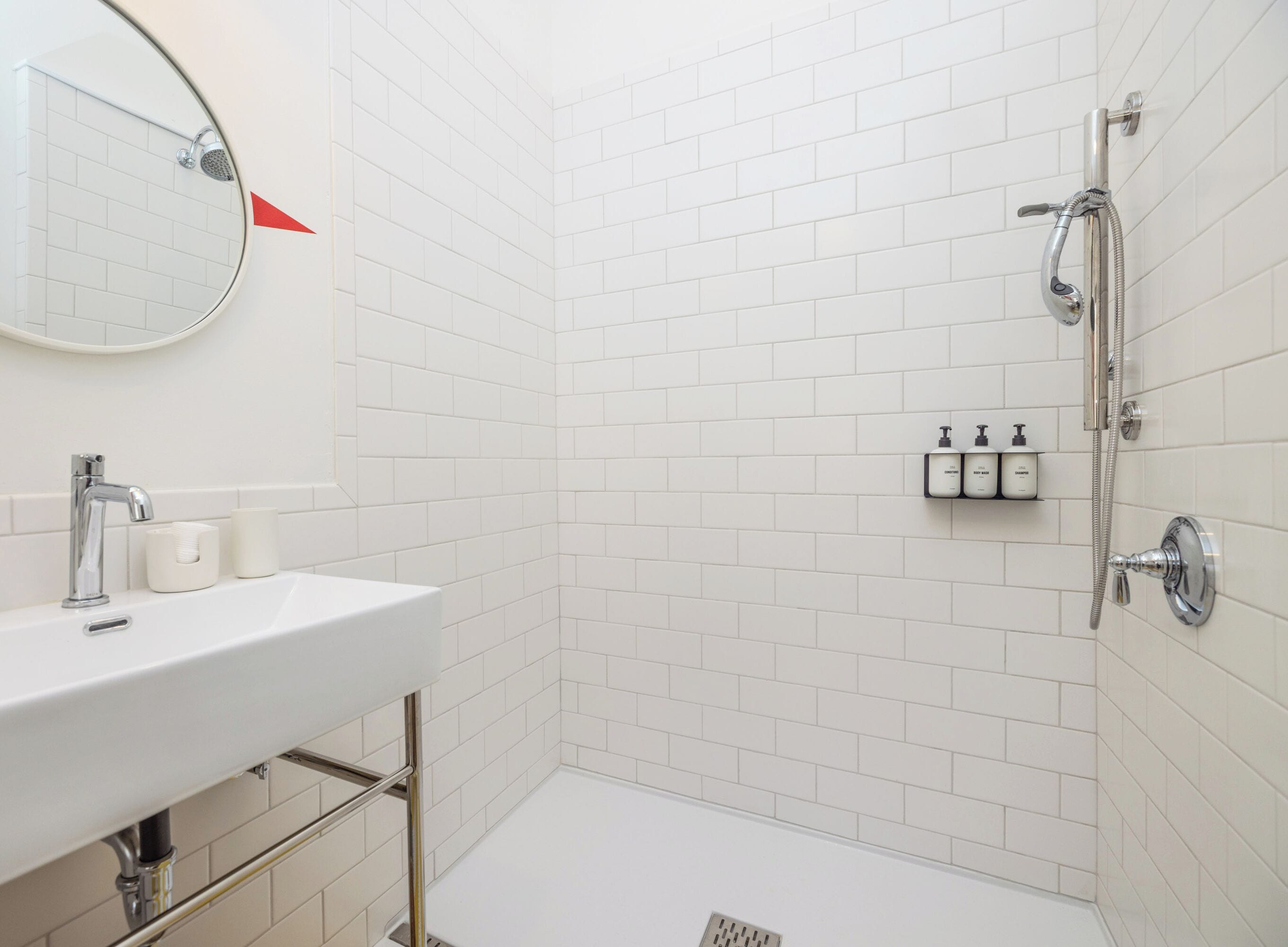Une salle de bain avec un lavabo blanc, un miroir et une douche.