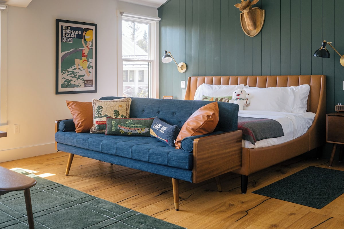 A bedroom with a bed, a blue sofa, and a wooden table.