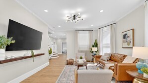 Un salon moderne avec un téléviseur à écran plat, un canapé en cuir et un tapis à motifs.
