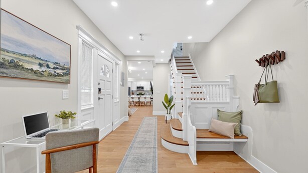 Un intérieur moderne avec un escalier, un bureau avec un ordinateur portable et, au fond, un coin repas.