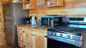 Une cuisine compacte avec des meubles en bois, un réfrigérateur en acier inoxydable, un four à micro-ondes et une cuisinière à gaz.