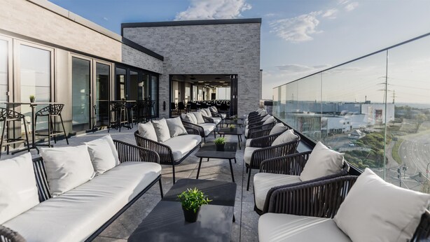 A rooftop terrace with outdoor seating, a modern building with large windows, and a view of the cityscape. - Aiden by Best Western Velbert (Velbert)