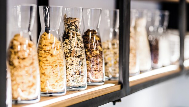 A shelf with multiple glass jars containing various grains and seeds.