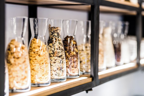 A shelf with multiple glass jars containing various grains and seeds.