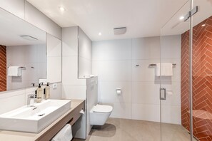 Ein modernes Badezimmer mit einem großen Spiegel, einem Waschbecken, einer Toilette und einer Duschkabine aus Glas.