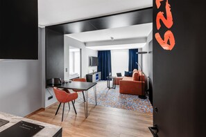 A modern hotel room with a dining area, a sofa, a TV, and a patterned carpet. - Aiden by Best Western Velbert (Velbert)