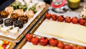 A variety of food items on a tray, including cheese, tomatoes, and other dishes.