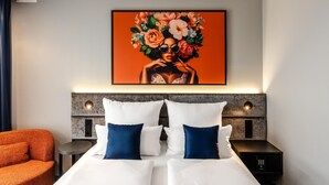 A hotel room with a bed, pillows, a nightstand, a wall-mounted artwork, and a chair. - Aiden by Best Western Velbert (Velbert)