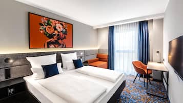 A hotel room with a bed, a desk, a chair, a TV, and a painting on the wall.