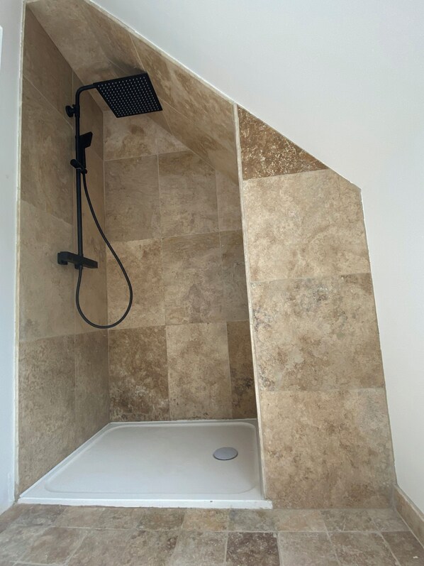 A shower area with a single showerhead and a handheld shower attachment, tiled walls, and a white floor. - Family home in Trébeurden close to beaches and hiking trails. (Trébeurden)