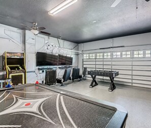A room with a foosball table, arcade games, and a large window.