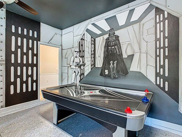 A pool table with Star Wars-themed wall art, including characters and a spaceship.