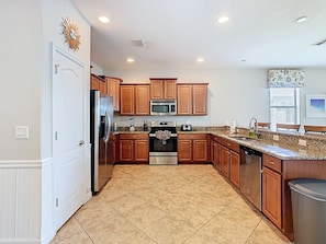 A kitchen with wooden cabinets, stainless steel appliances, and a granite countertop.