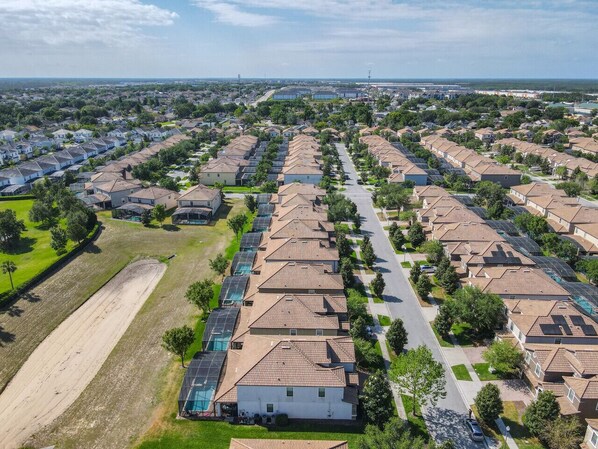 Um bairro residencial com casas padronizadas, uma via principal e áreas verdes.