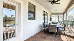 A covered patio with a brick floor, a dining table with chairs, and a ceiling fan. - Stunning 8BR Villa with Private Pool & Gameroom (Four Corners)