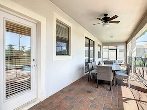 A covered patio with a brick floor, a dining table with chairs, and a ceiling fan. - Stunning 8BR Villa with Private Pool & Gameroom (Four Corners)