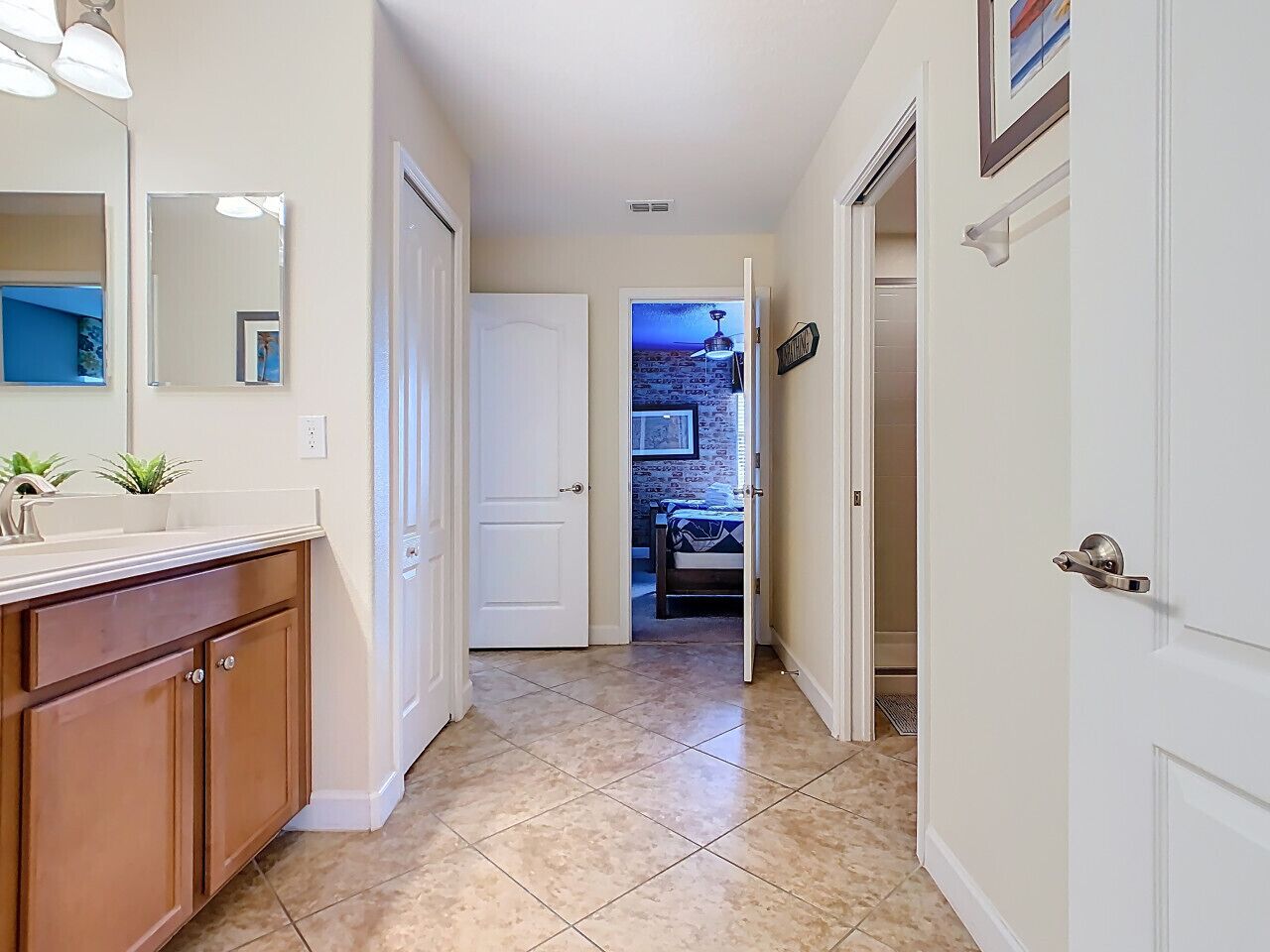 Un couloir avec une salle de bain, une porte donnant sur une chambre et un sol carrelé.