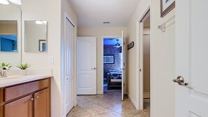 A hallway with a bathroom, a door leading to a bedroom, and a tiled floor. - Stunning 8BR Villa with Private Pool & Gameroom (Four Corners)