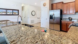 A modern kitchen with granite countertops, stainless steel appliances, wooden cabinets, and a large window. - Stunning 8BR Villa with Private Pool & Gameroom (Four Corners)