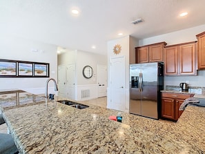 A modern kitchen with granite countertops, stainless steel appliances, wooden cabinets, and a large window. - Stunning 8BR Villa with Private Pool & Gameroom (Four Corners)