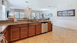 A spacious kitchen with granite countertops, wooden cabinets, and a stainless steel dishwasher. - Stunning 8BR Villa with Private Pool & Gameroom (Four Corners)