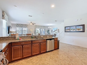 A spacious kitchen with granite countertops, wooden cabinets, and a stainless steel dishwasher. - Stunning 8BR Villa with Private Pool & Gameroom (Four Corners)