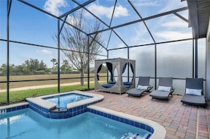 A pool area with a hot tub, lounge chairs, and a covered seating area.