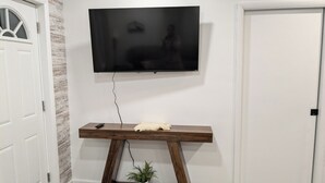 Een moderne woonkamer met een wandtelevisie, een houten salontafel en een potplant.