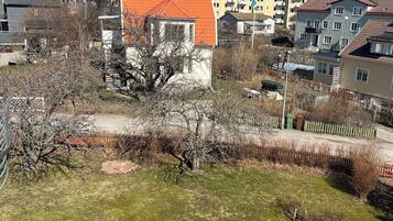 Zona residencial con una mezcla de arquitectura moderna y tradicional, incluyendo una casa con techo rojo y un árbol grande en primer plano.
