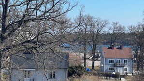Une maison à deux étages, avec un toit recouvert de tuiles rouges, un balcon et une petite fenêtre.