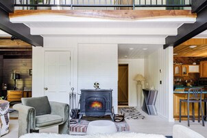 A modern living room with a fireplace, a sofa, and a dining area with a bar.
