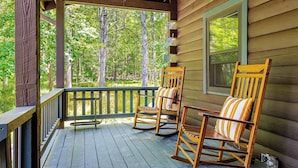 A wooden porch with two rocking chairs and a window overlooking a forest. - Pool+hot Tub, Firepit Near Hikes, Shops, Dining Cragswood Lodge by Avantstay (New Paltz)