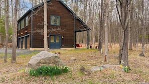 A wooden cabin with a porch, large windows, and a door.