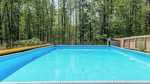 A swimming pool surrounded by a wooden fence and trees.