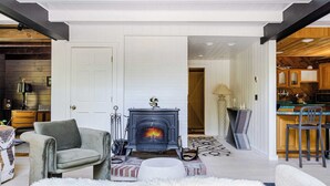A modern living room with a fireplace, a sofa, and a dining area with a bar. - Pool+hot Tub, Firepit Near Hikes, Shops, Dining Cragswood Lodge by Avantstay (New Paltz)