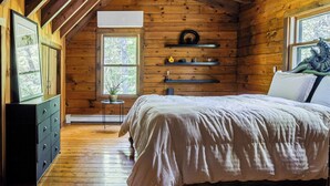 A wooden cabin bedroom with a bed, dresser, shelves, and a ceiling fan. - Pool+hot Tub, Firepit Near Hikes, Shops, Dining Cragswood Lodge by Avantstay (New Paltz)