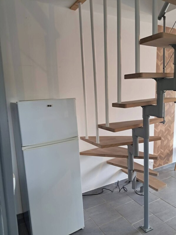 Una cocina moderna con un refrigerador blanco, estantes de madera y un revestimiento de pared con patrón de espiga.
