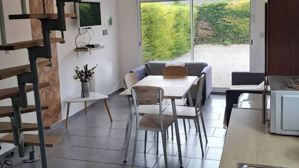 Een moderne keuken met een inbouwmagnetron, een eethoek met een tafel en stoelen, en een trap naar een hoger niveau.