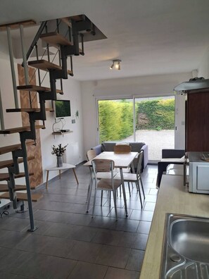 A modern kitchen with a built-in microwave, a dining area with a table and chairs, and a staircase leading to an upper level. - L'échappée Verte, small 2-bedroom house / 25min from Site des 2 Caps (Guînes)