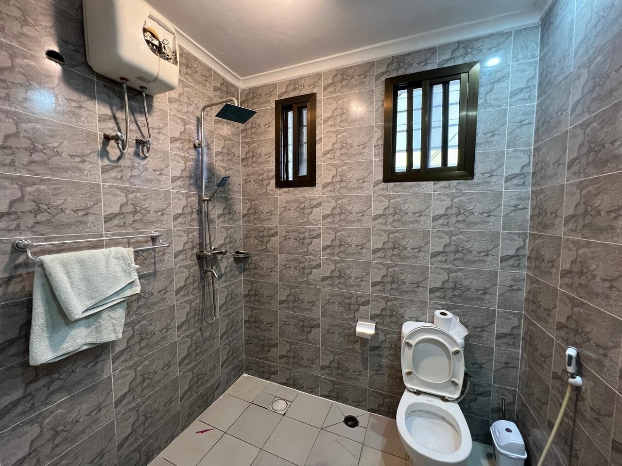 A bathroom with a shower, toilet, and towel rack.