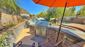An outdoor patio with a grill, seating, and a pool. - Pickleball Court! +GIANT Pool w/Waterslide! Game Room, Hot Tub, Golf+ (Mesa)