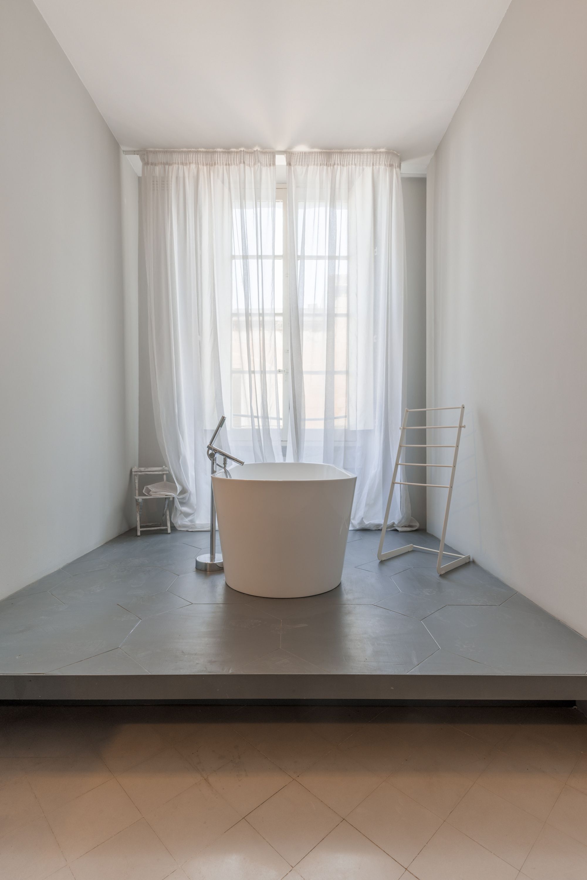 Een strakke badkamer met een vrijstaand bad, een handdoekrek en een droogrek.